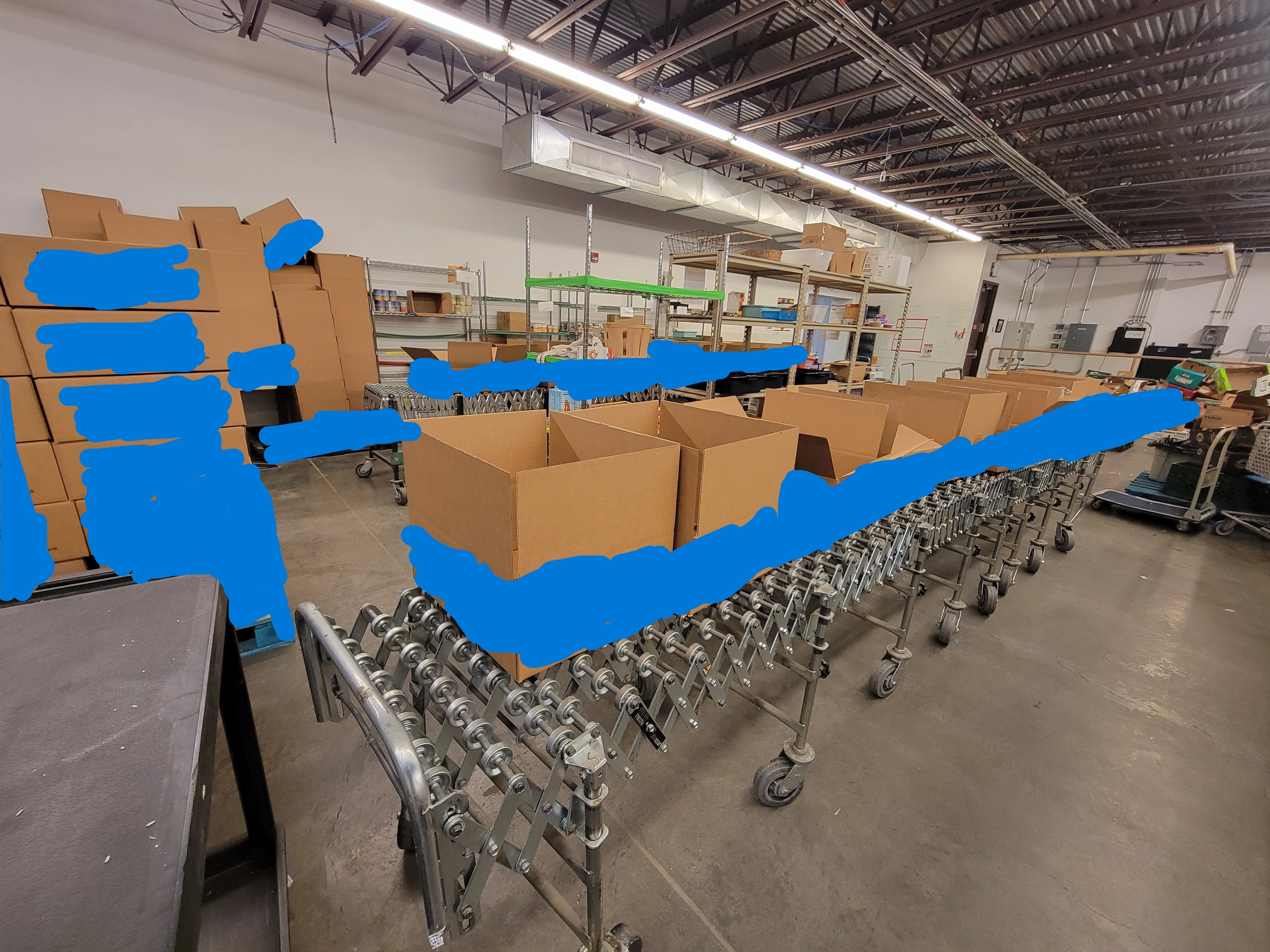 Coveyor box full of boxes with boxes and shelves behind it.